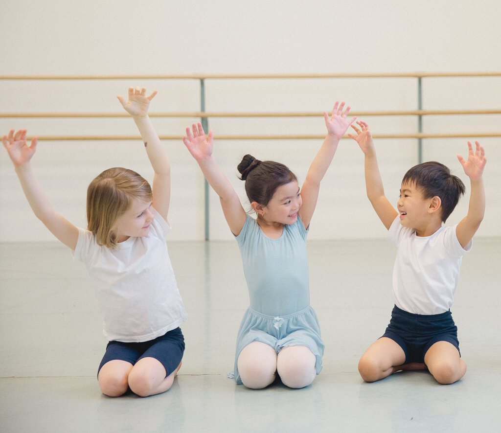 Young children with different ethnic backgrounds laughing and smiling at each other as they play and dance.