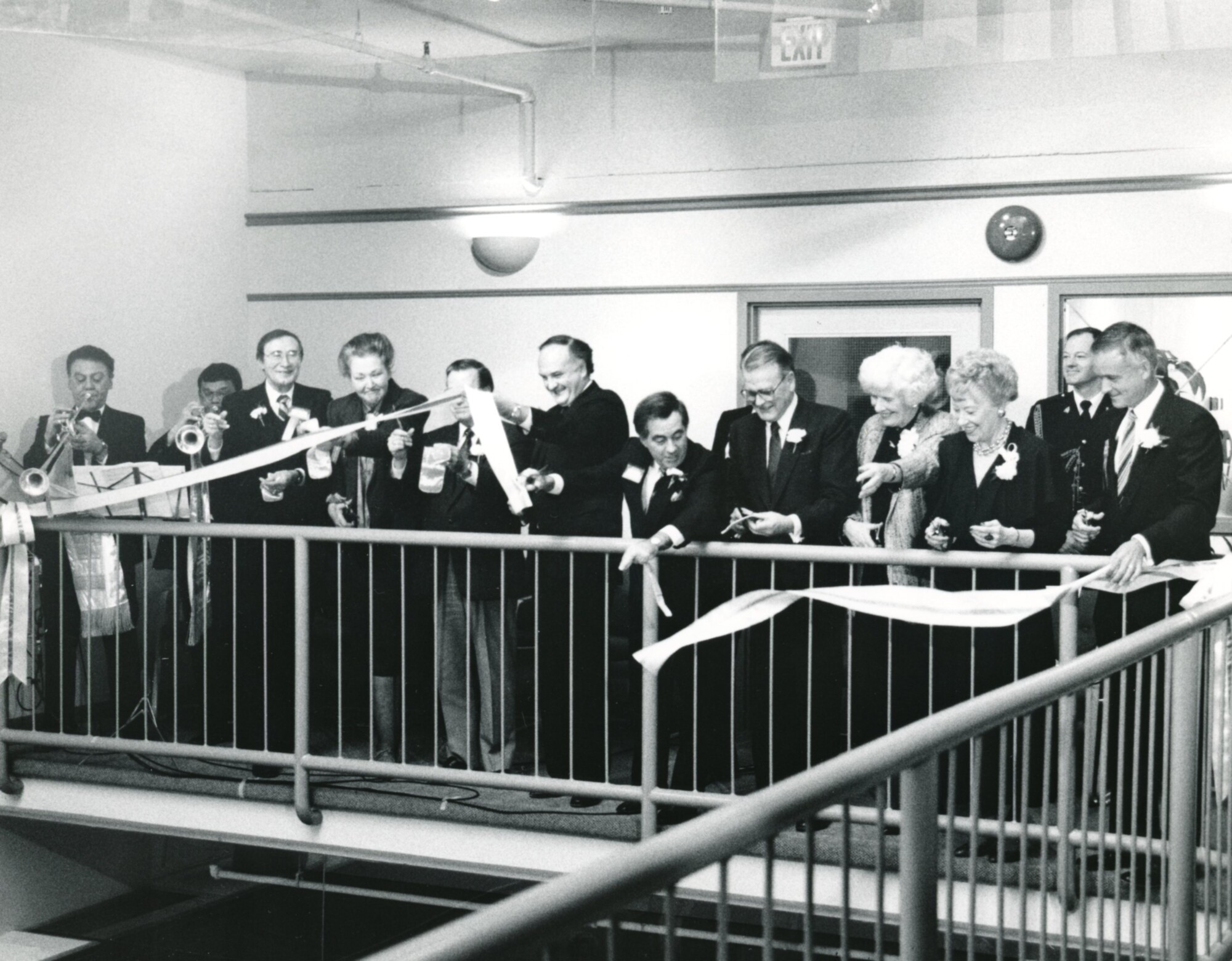 a black and white photo of Ribbon Cutting Ceremony in 1988. Musicians and people are gathered cutting a ribbon from the second floor balcony